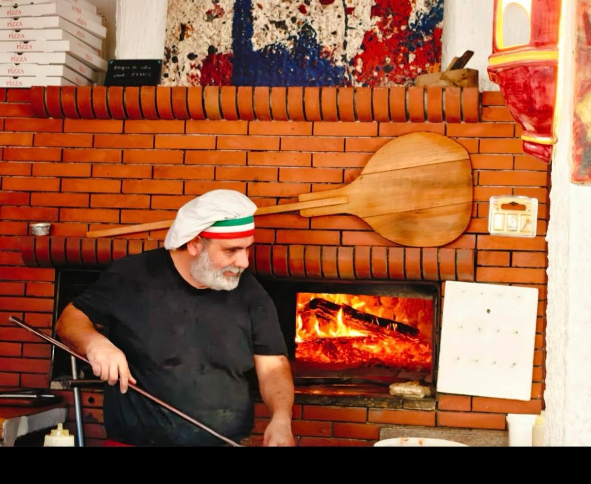 Le pizzaiolo devant le four à bois en briques